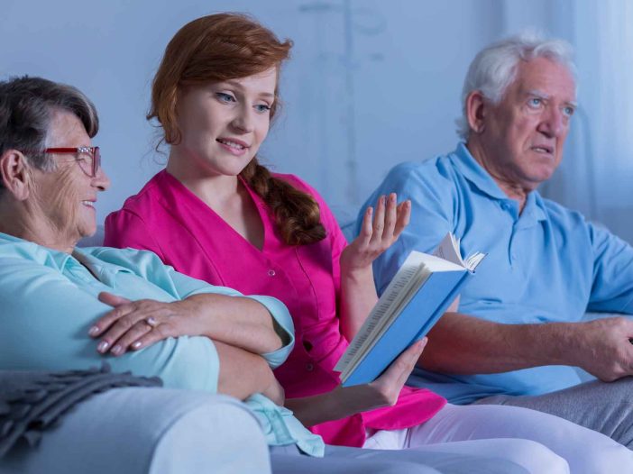 assisted living care facility worker reading a book to residents